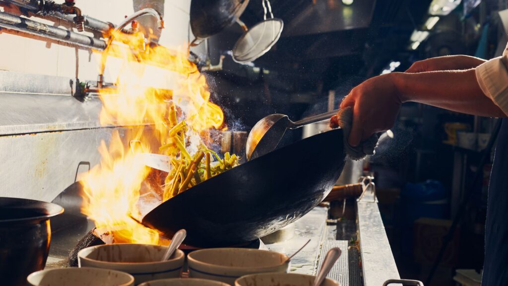 A man is preparing food in a wok.
